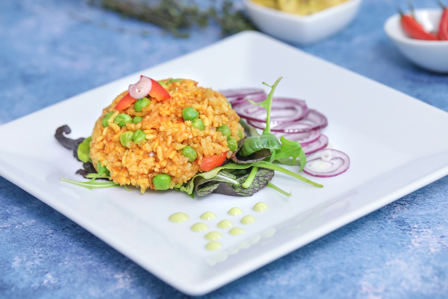 A colourful plate of jollof rice with vegetables and fresh greens