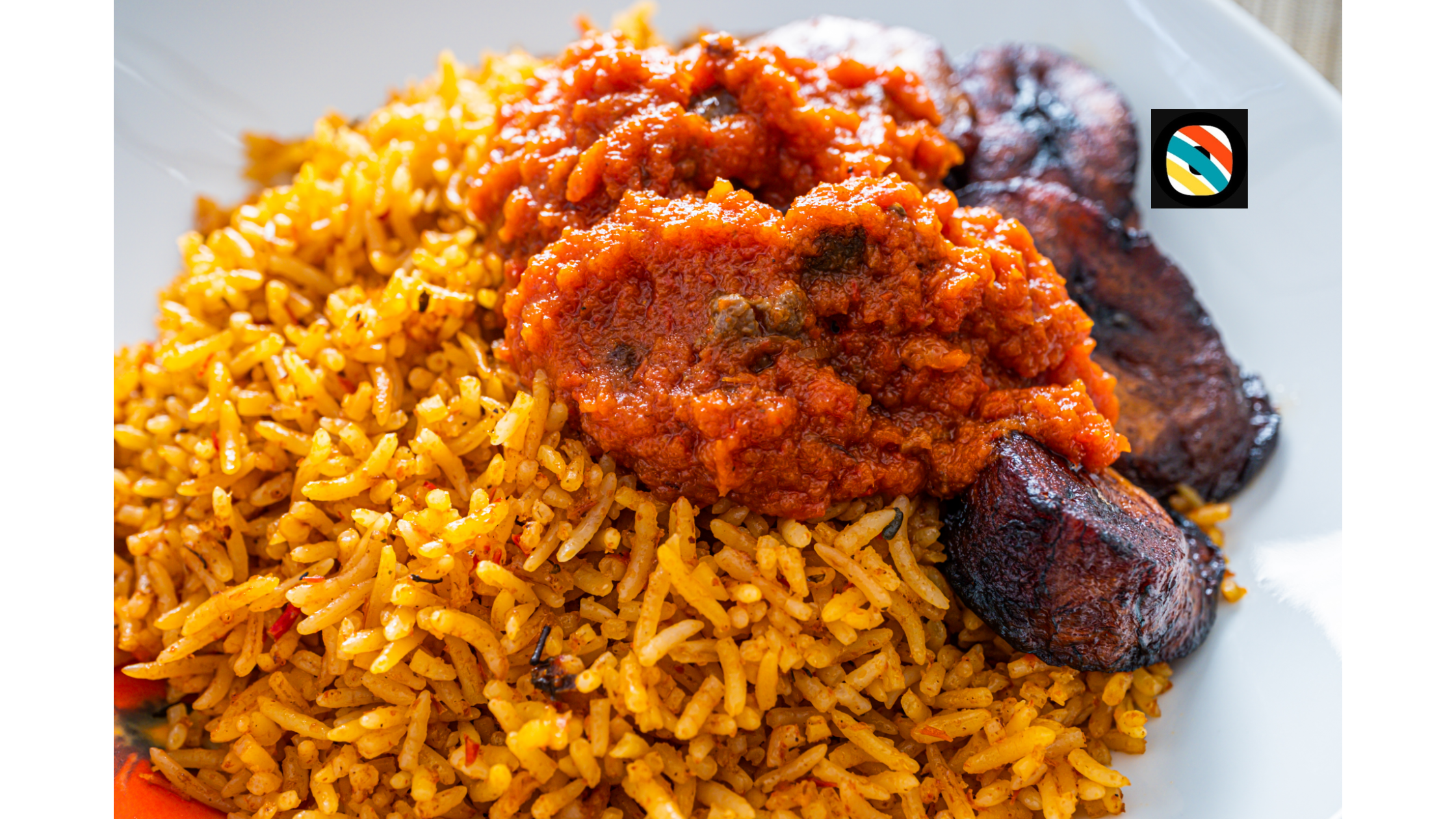 A plated serving of Nigerian jollof rice with vegetables and greens